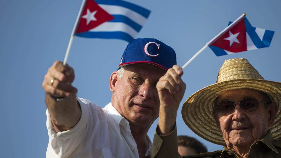 Cuba's President Miguel Díaz-Canel, left, and former Cuban President Raúl Castro, wave national flags as they watch the May Day parade file past at Revolution Square, in Havana, Cuba, Tuesday, May 1, 2018.