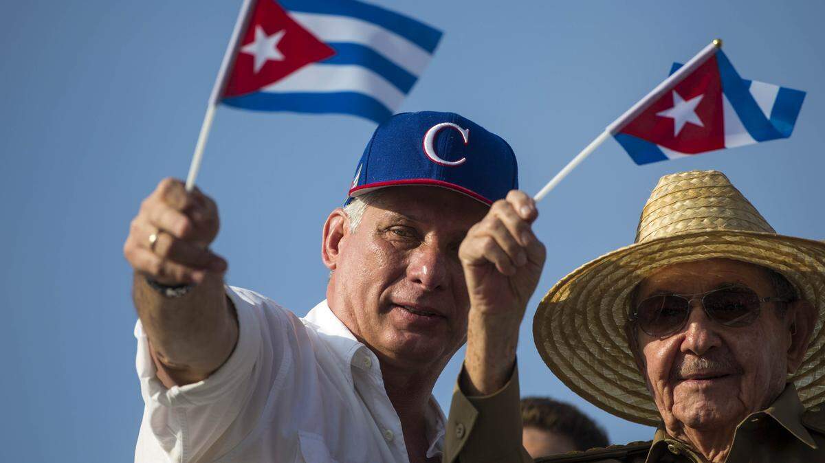 Cuba's President Miguel Díaz-Canel, left, and former Cuban President Raúl Castro, wave national flags as they watch the May Day parade file past at Revolution Square, in Havana, Cuba, Tuesday, May 1, 2018.
