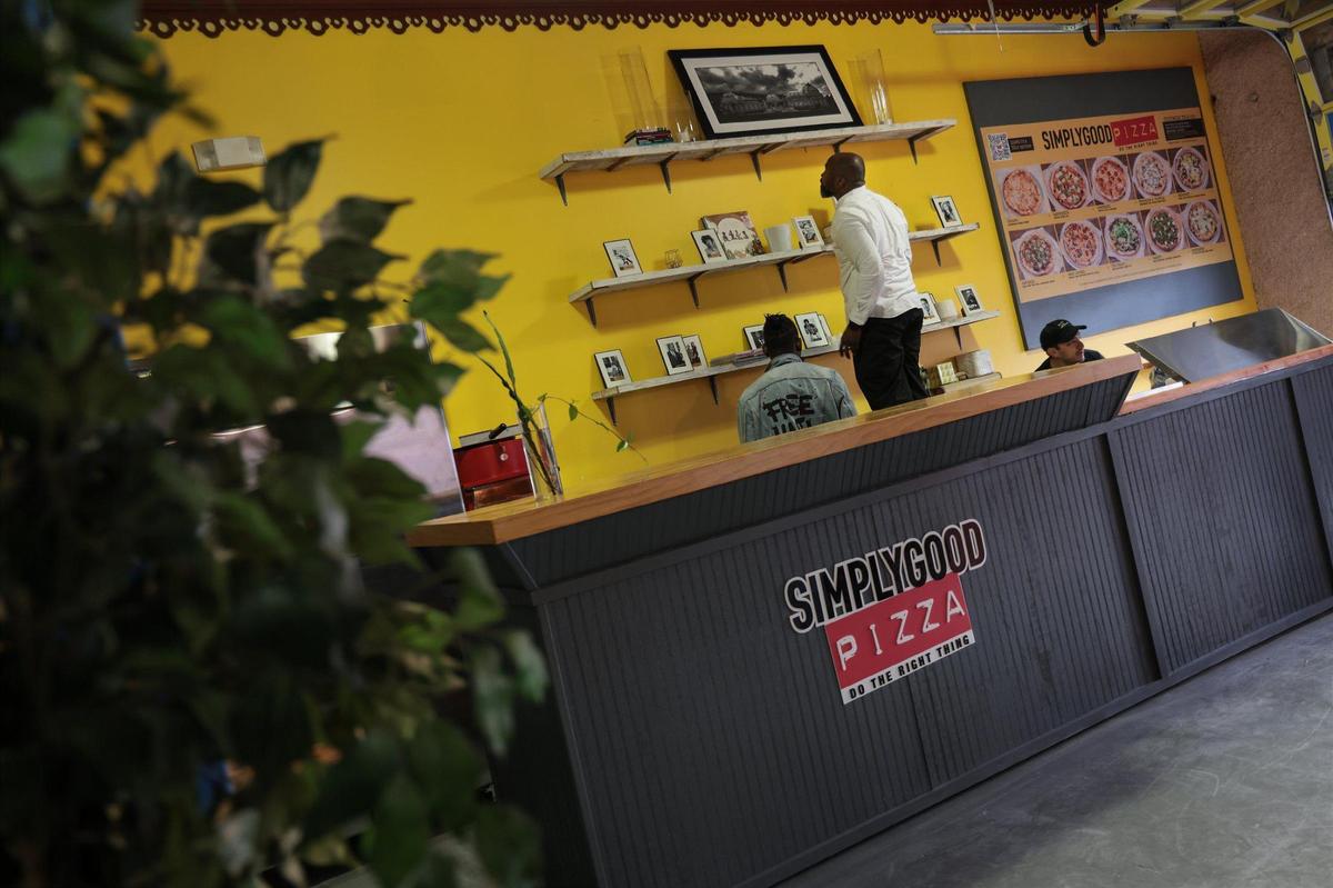 Max Pierre, operator of SimplyGood Pizza puts some final touches on his pizza bar at the Caribbean Marketplace.