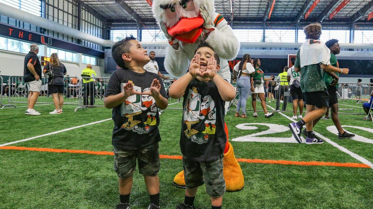 Roger Avila, 6, and Ryan Avila, 4, pose for photos with Sebastian the Ibis at Carol Soffer Indoor Practice Facility during CanesFest at the University of Miami in Coral Gables on Saturday, August 6, 2022.