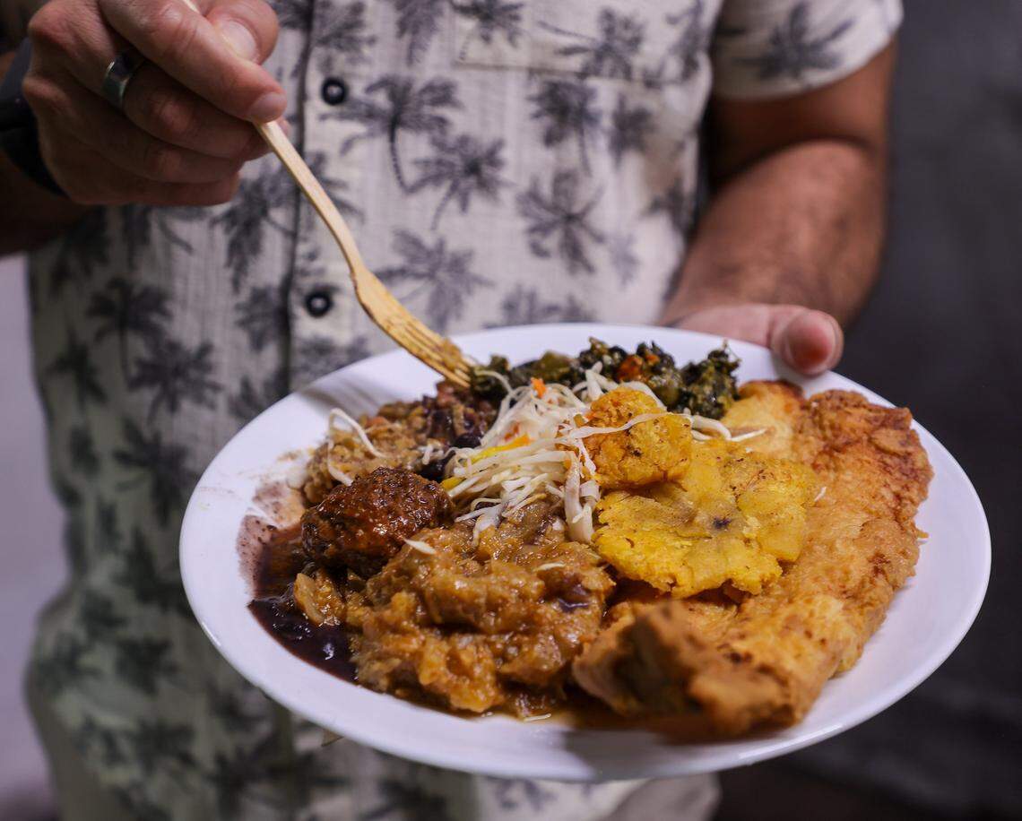 Omaar Yemini, co-owner of Naomi's Garden, eats a plate of legumes, fish and other traditional Haitian dishes at the Little Haiti restaurant, Thursday, Jan. 15, 2026, in Miami, Florida.
