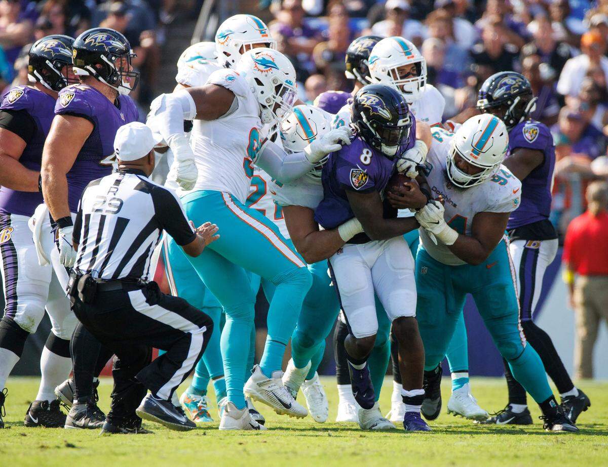 Miami Dolphins players Emmanuel Ogbah (91) Zach Sieler (92) and tackle Christian Wilkins (94) stop Baltimore Ravens quarterback Lamar Jackson (8) during fourth quarter of an NFL football game at M&T Bank Stadium on Sunday, September 18, 2022 in Baltimore, MD.
