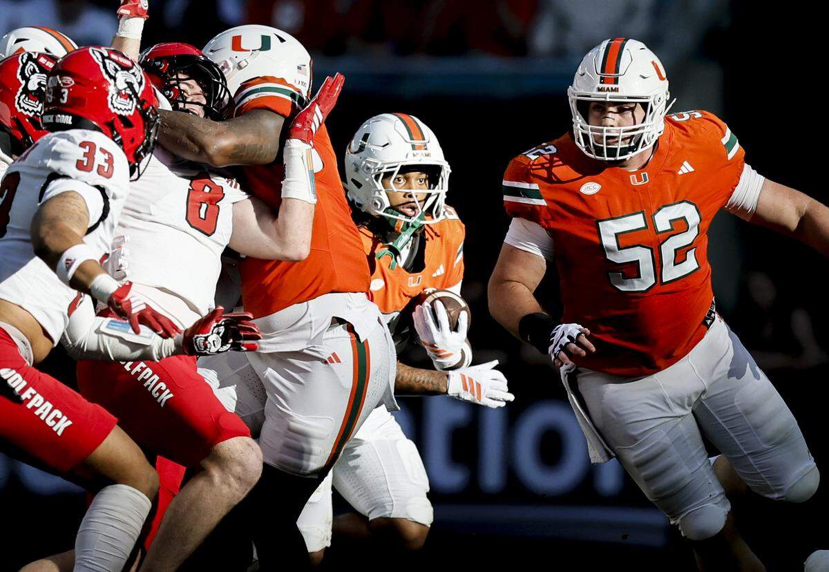Miami Hurricanes running back Girard Pringle Jr. (22) carries the ball out of the shadows in the first half of an NCAA football game against the NC State Wolfpack at Hard Rock Stadium in Miami Gardens, Florida, on Saturday, November 15, 2025.