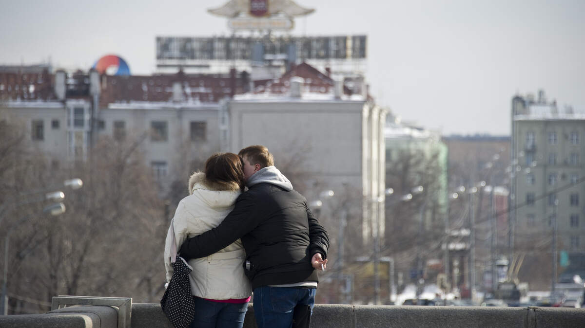 A couple embraces on a bridge overlooking the Moscow river in the center of Moscow on February 29, 2012.