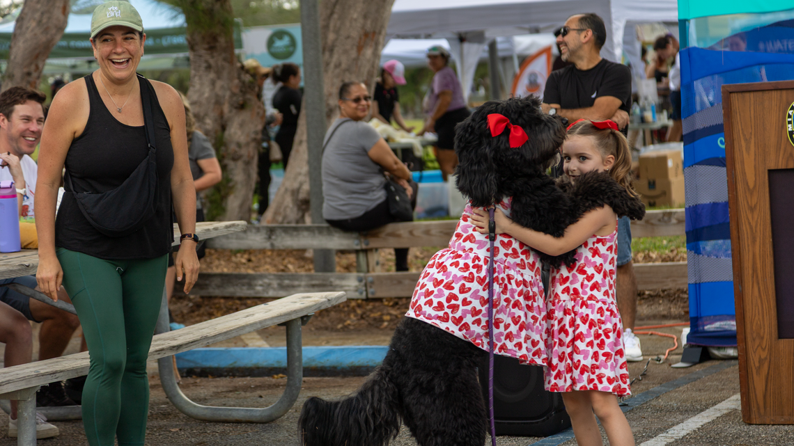 Lucia Motes, who won the dog lookalike contest, hugs her dog Luna Katz. The event at Tropical Park on Sunday helped raise awareness for how unpicked up dog poop gets into our water which can cause fish kills and illness.