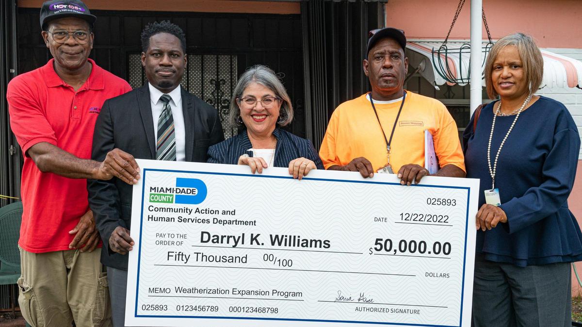 From left, Rodney Baltimore, a Hot 100 personality, Miami-Dade County’s Energy, Facilities, and Transportation Division Director Adrian Frazier, Miami-Dade County Mayor Daniella Levine Cava, homeowner Darryl Williams and Community Action and Human Services Director Sonia Grice pose in front of Williams’ home outside of Miami on Thursday, Dec. 22, 2022.