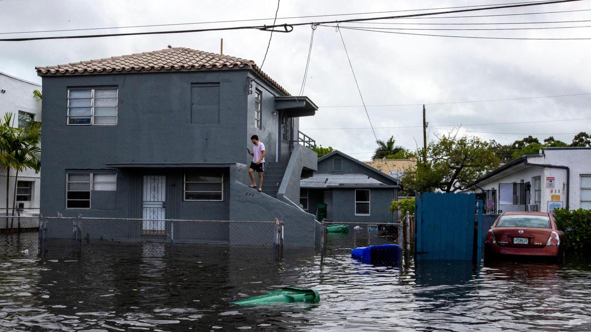 A person stands on a house surrounded by floodwaters on Southwest Third Street in the Little Havana neighborhood of Miami, Florida, on Saturday, June 4, 2022.
