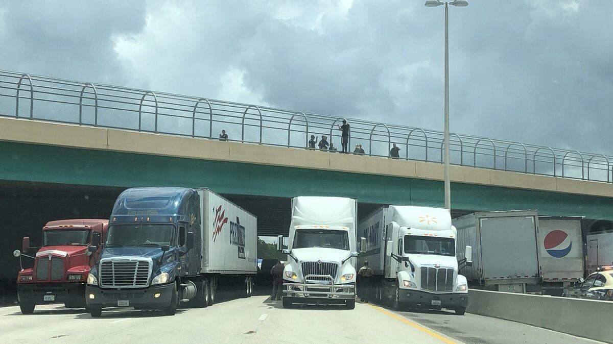 At least seven semi trucks pull up under a Florida’s Turnpike overpass in Orlando after the Florida Highway Patrol and law enforcement reported that a man was perched above the roadway and looked as if he was about to jump. The trucks lined up to shorten the man’s fall should he jump. He did not, FHP said, and the road was opened on Tuesday afternoon, Aug. 28, 2018.