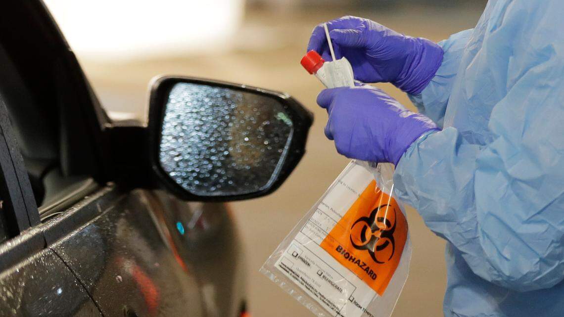 A nurse at a drive up COVID-19 coronavirus testing station, set up by the University of Washington Medical Center, holds a swab used to take a sample from the nose of a person in their car, Friday, March 13, 2020, in Seattle.
