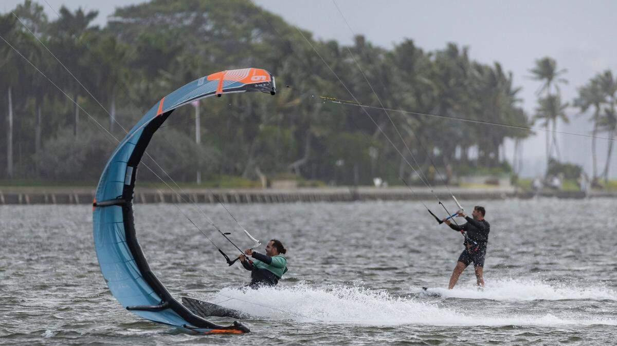 Kite boarders catch waves as rain makes its way over the area as seen from Matheson Hammock Park on Tuesday, April 11, 2023, in Coral Gables, Fla.