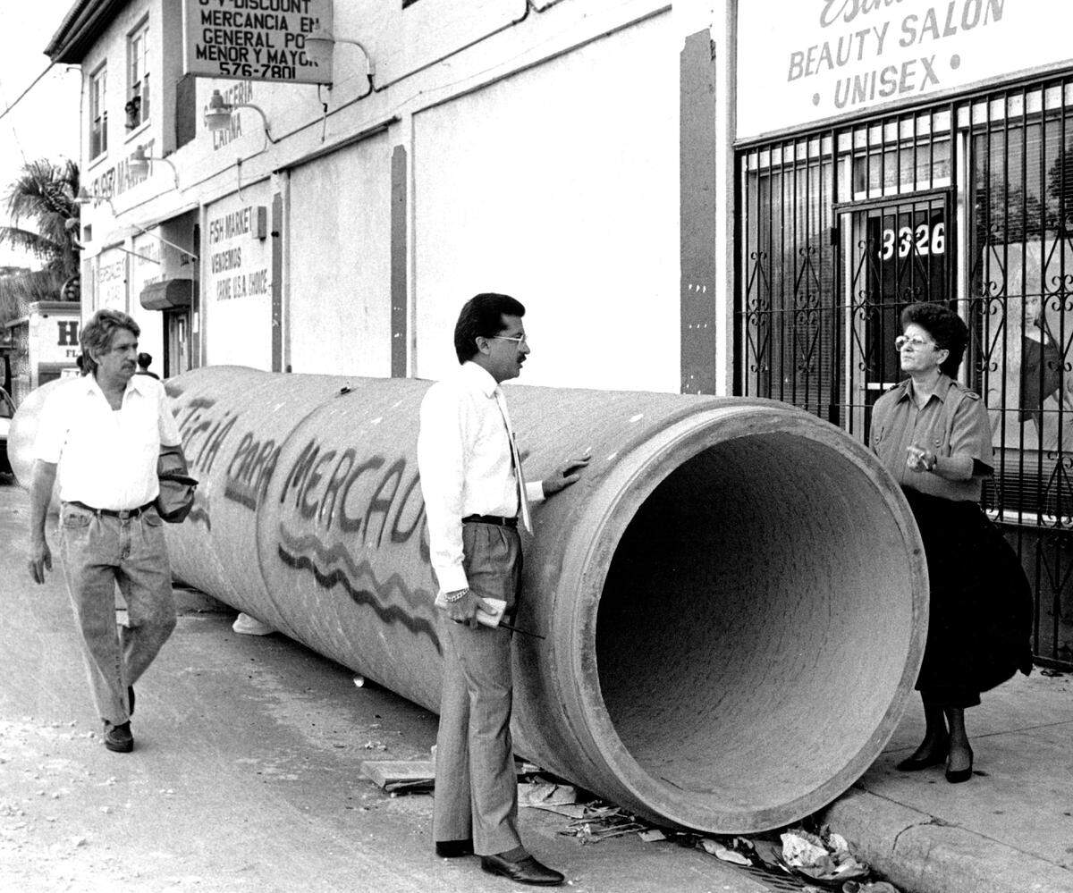Eleno Alvarez, owner of Robert Super Market on Second Avenue between 33 and 34th Streets, approaches Fred Santiago and Mrs. Elena Alvarez as they talk over the construction problems plaguing their neighborhood.