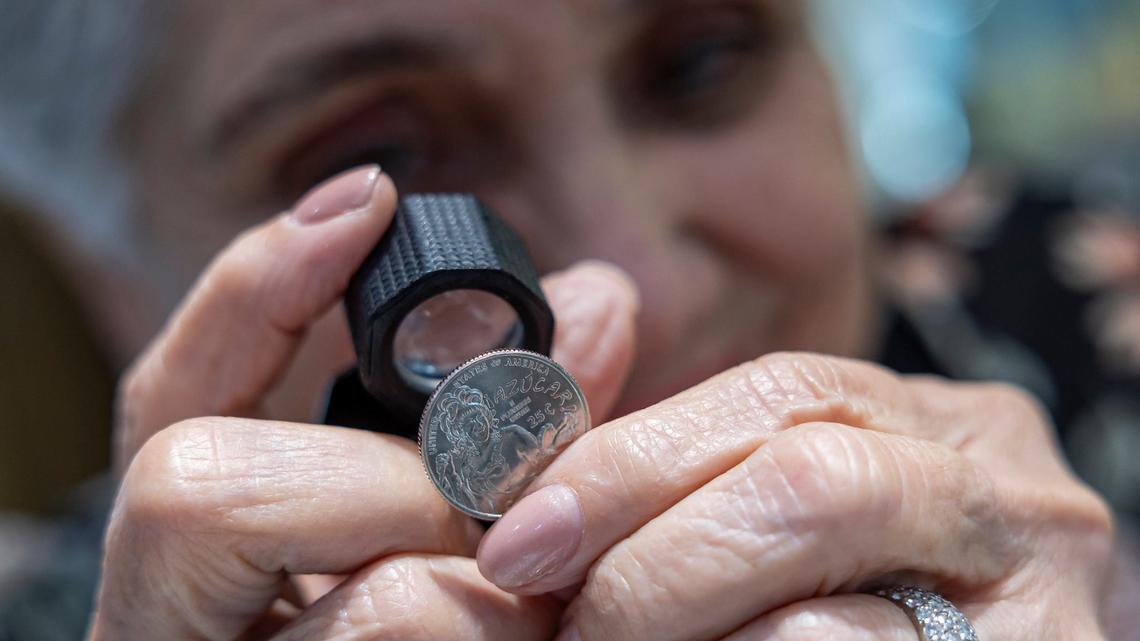 Marisa Santayana, 80, inspects a Celia Cruz-themed quarter at her jewelry store on Monday, Aug. 19, 2024, in Miami, Fla. Santayana is designing a special pendant that will allow customers to wear the Celia Cruz quarter. The coin is part of the U.S. Mint’s American Women Quarters Program, which aims to celebrate the accomplishments and contributions made by women of the United States.