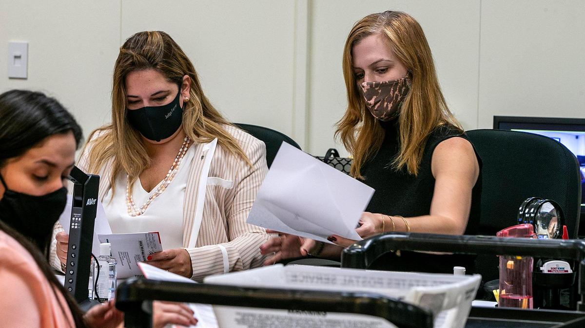 Miami-Dade canvassing board members, County Judge Victoria Ferrer, left, and Christina White, Supervisor of Elections, right, review irregular mail-in ballots during an October meeting.