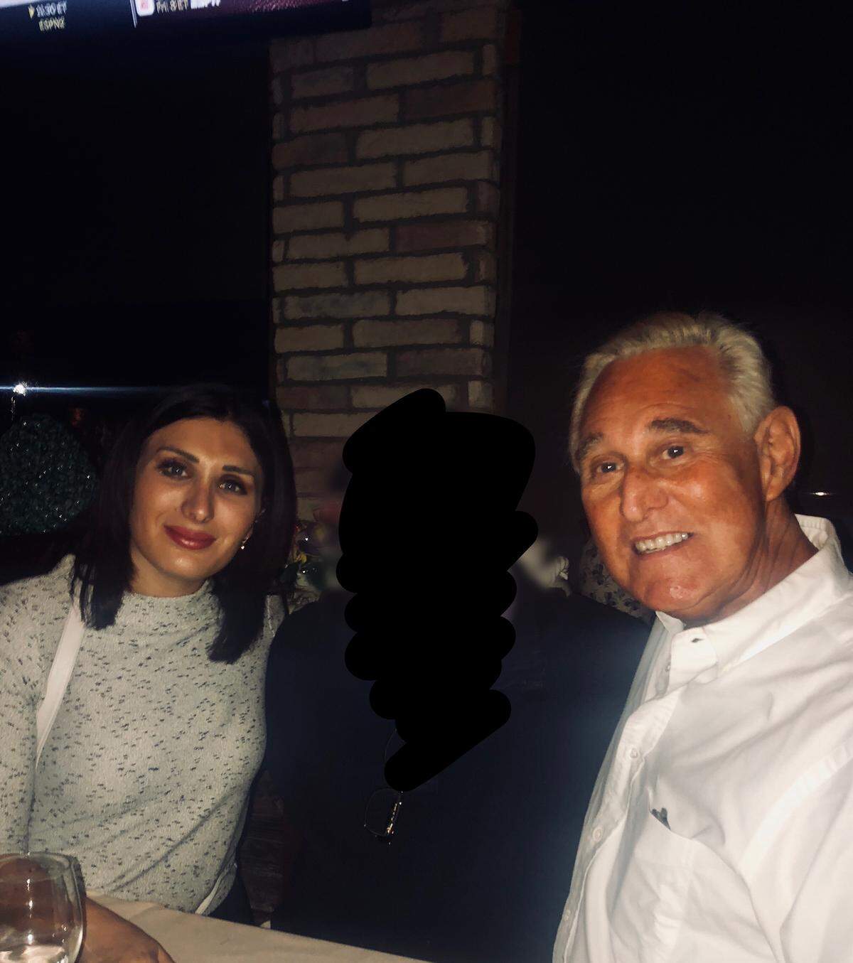 Laura Loomer, left, and Roger Stone pose at Thanksgiving dinner with Loomer’s father, who was obscured by Loomer before she published the photograph.