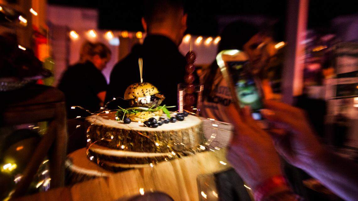 A woman takes a photo of one of the dozens of burgers at the 2019 South Beach Wine & Food Festival’s Burger Bash. A panel of judges, headlined by David Burtka and Neil Patrick Harris, choose the winners on Feb. 22.