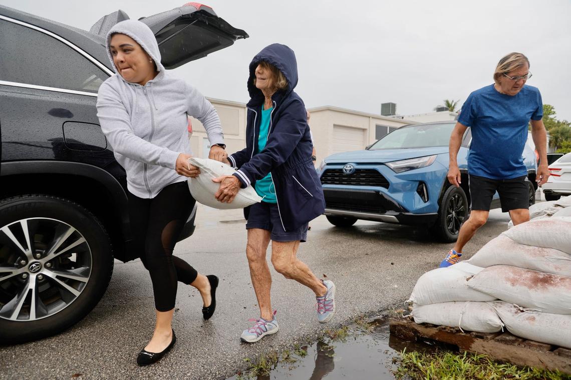 Hairan Sion, left, and Diana Eustice team up to carry a sandbag to Eustice’s car at the City of Oakland Park maintenance yard on Friday, June 3, 2022. Eustice said she needed to protect her garage entrance from the heavy rain expected from Tropical Storm Alex.