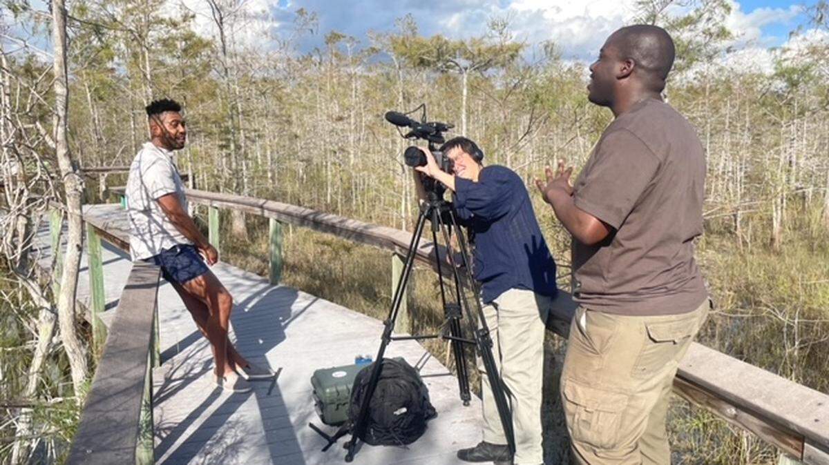 Cornelius Tulloch, right, directs filmmaker Alexa Caravia and AIRIE Fellow Kunya Rowley in the creation of a piece for “Passages.” In the immersive installation, Rowley performs a song he wrote that was inspired by his time as an AIRIE resident artist in the Everglades.