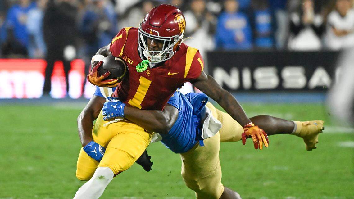 Nov 23, 2024; Pasadena, California, USA; USC Trojans wide receiver Zachariah Branch (1) is tackled by UCLA Bruins linebacker Jalen Woods (17) during the second quarter at Rose Bowl. Mandatory Credit: Robert Hanashiro-Imagn Images
