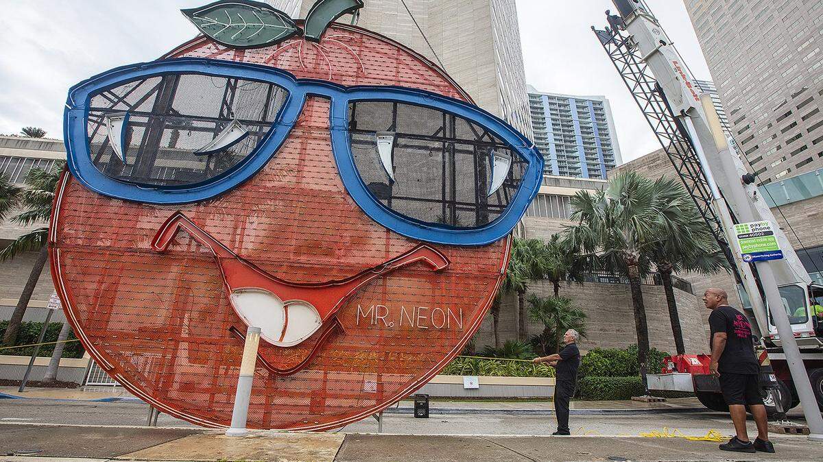 Steve Carpenter, known as "Mr. Neon" (center), works on the Big Orange installation, a hallmark of Miami's NYE tradition, with assistance from Joe Holley (right/front) on Dec. 27, 2024, at the InterContinental Hotel in Downtown Miami. It will be a chilly 50 degrees or lower when the sign rises around midnight on New Year’s Eve Dec. 31, 2025.