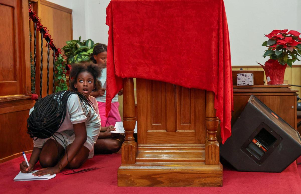 Jalani Lambright, 11, left, Jelaine Richards, 10, and Jayilah Lambright, 12, right, finish homework at Macedonia Missionary Baptist Church before rehearsing for their upcoming play “The Birth of Jesus.”