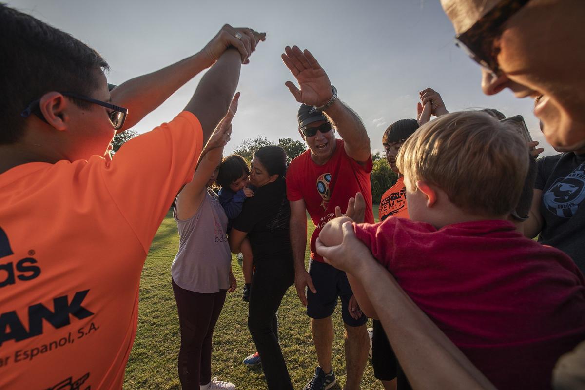 Coach Antonio Paz stands with kids playing at soccer field in Pinecrest Gardens.