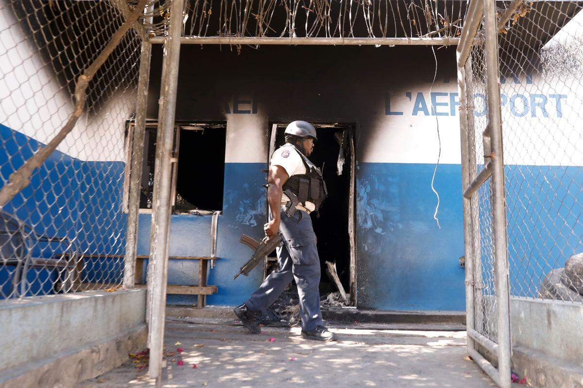 Un agente de la policía pasa por delante de una comisaría incendiada por pandillas armadas en Puerto Príncipe, Haití, el martes 5 de marzo de 2024.