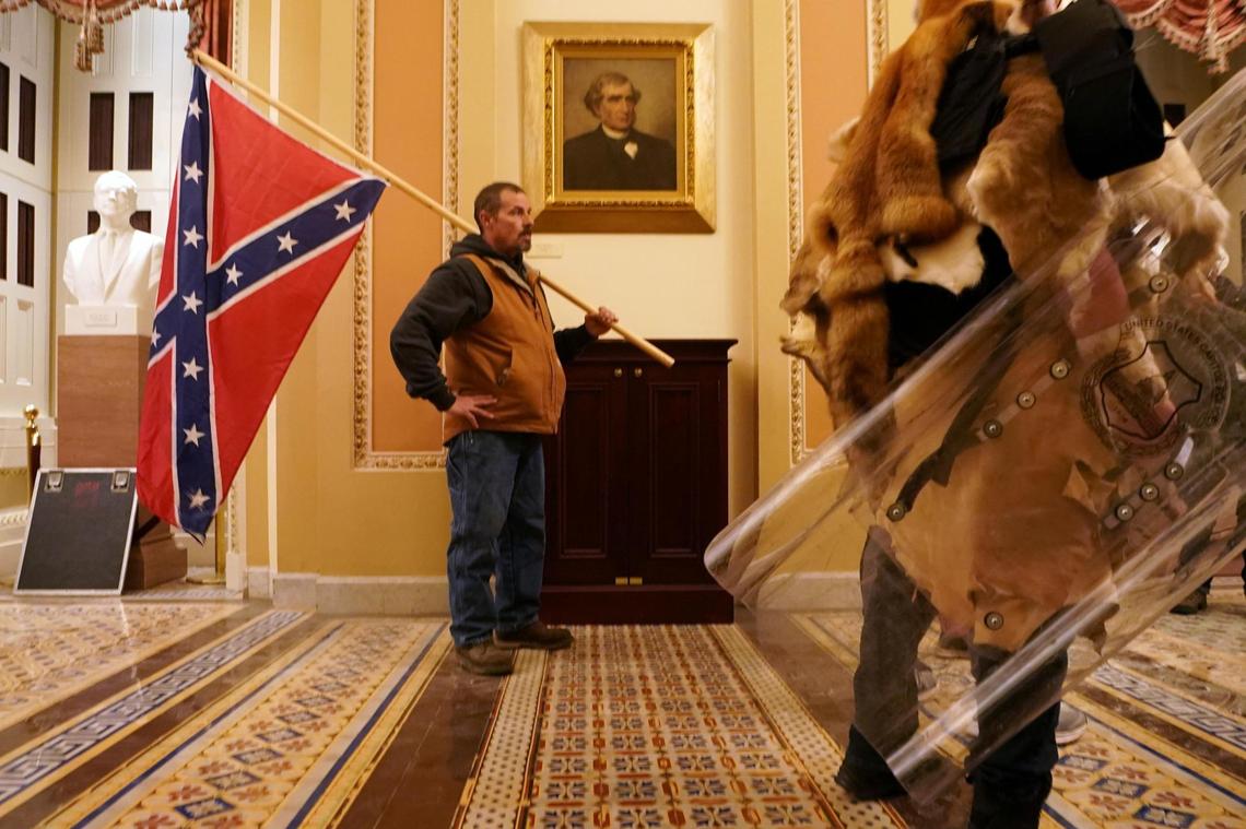 A Trump supporter carries the Confederate flag inside the Capitol as Congress met to certify President-elect Joe Biden’s victory, on Wednesday, Jan. 6, 2021.