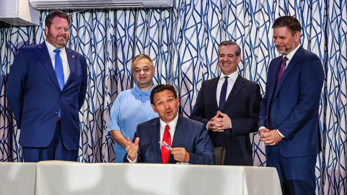 El gobernador  Ron DeSantis firma un proyecto de ley que prohíbe a las personas sin hogar dormir en lugares públicos, durante una conferencia de prensa en el restaurante Santorini by Georgios, en South Beach, el martes 20 de marzo de 2024. DeSantis elogió una medida similar en Miami Beach que el alcalde Steven Meiner (segundo por la derecha) calificó de "dura" pero "compasiva". También estuvieron presentes el senador estatal Jonathan Martin (izquierda), el representante Sam Garrison (derecha) y el propietario de Santorini by Georgios, Georgios Vogiatzis (segundo por la izquierda).