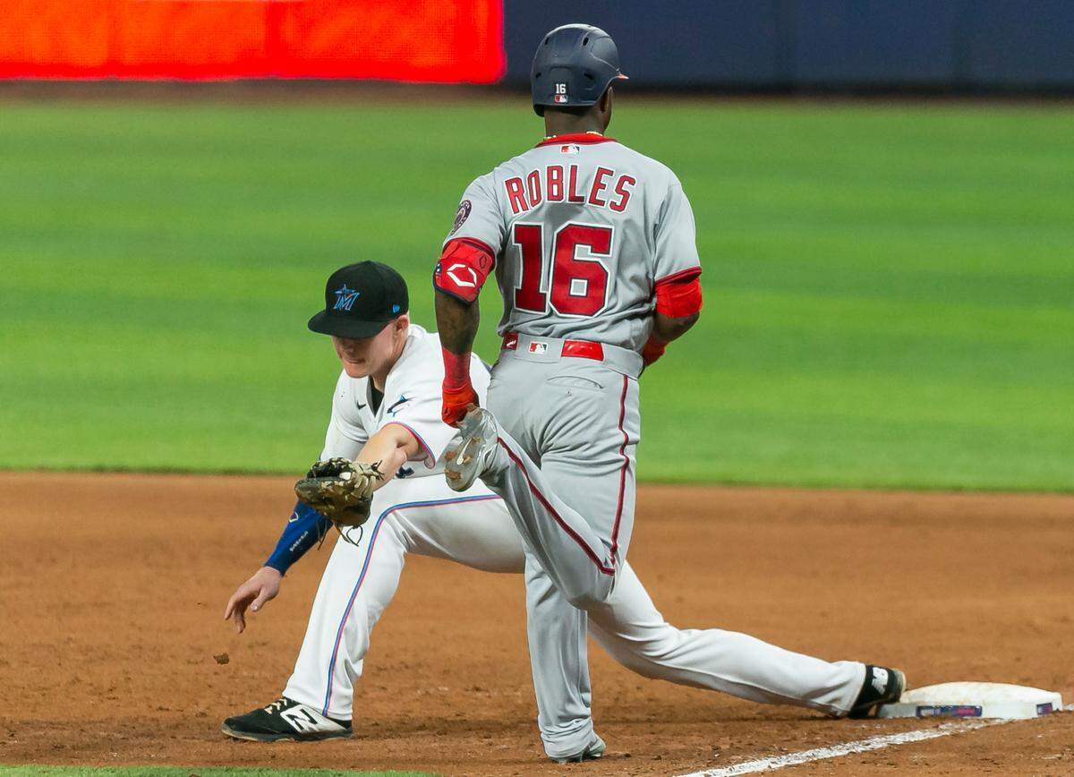 Miami Marlins first baseman Garrett Cooper (26) tags Washington Nationals center fielder Victor Robles (16) out at first base during the ninth inning of their baseball game at LoanDepot Park on Monday, May 16, 2022, in Miami, Florida.