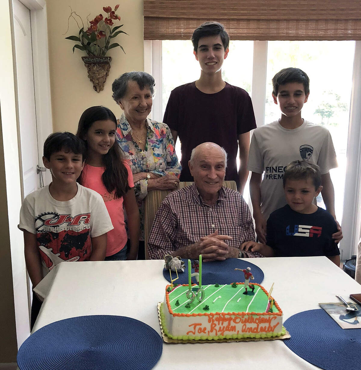 Joe Reisman and his wife, Norma, with their great grandchildren, enjoy a University of Miami Hurricanes-themed cake at the recent shared family birthday party.