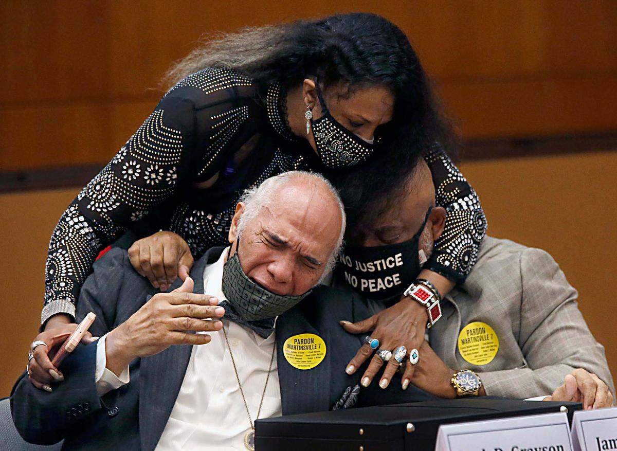 Rose Grayson, niece of Francis DeSales Grayson, top, comforts James Grayson, son of Francis DeSales Grayson, left, and Rudy MCollum, great nephew of Francis DeSales Grayson, one of the Martinsville Seven, after Virginia Governor Ralph Northam issued posthumous pardons for Grayson and the other six members during a ceremony inside the Patrick Henry Building in Richmond, Va. Tuesday, Aug. 31, 2021. Gov. Northam granted posthumous pardons to seven Black men who were executed in 1951 for the rape of a white woman, in a case that attracted pleas for mercy from around the world and in recent years has been denounced as an example of racial disparity in the use of the death penalty. (Bob Brown/Richmond Times-Dispatch via AP)