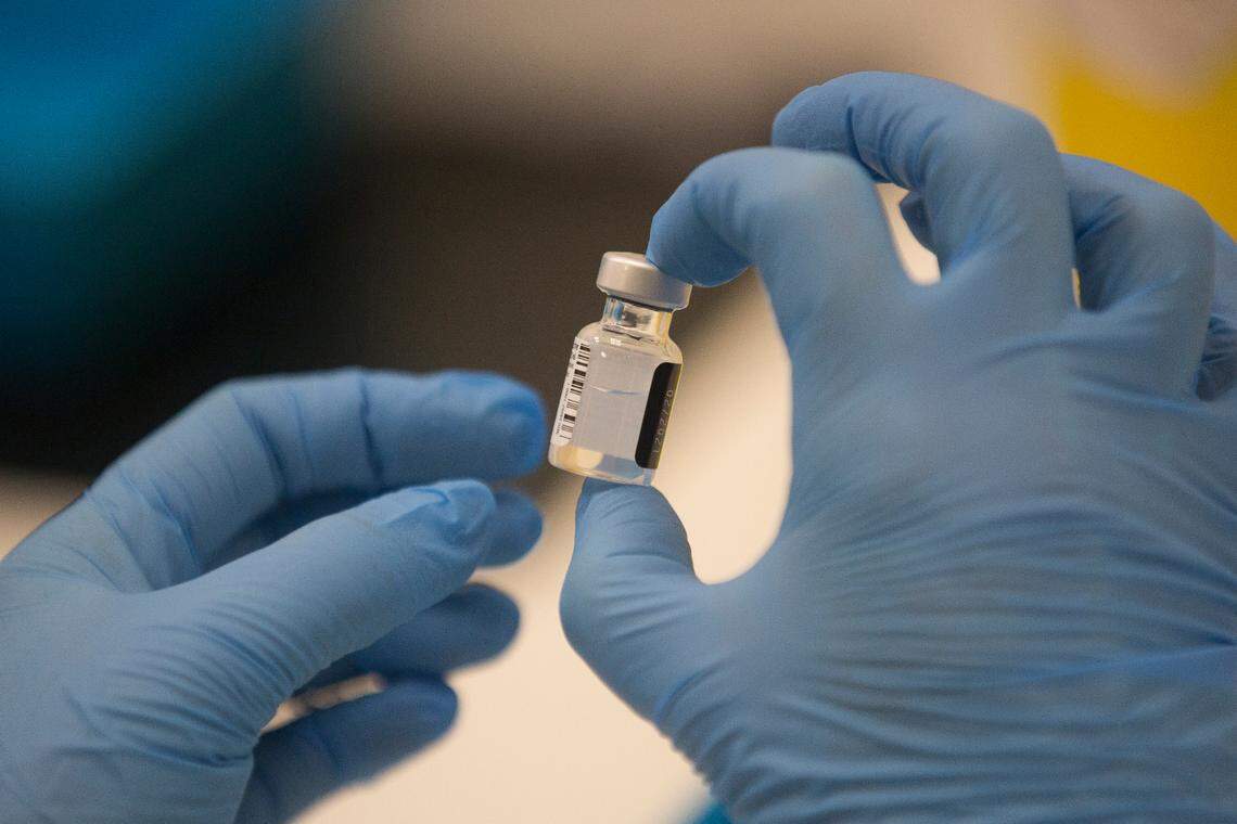 A worker holds a bottle of the Pfizer-BioNTech COVID-19 vaccine.