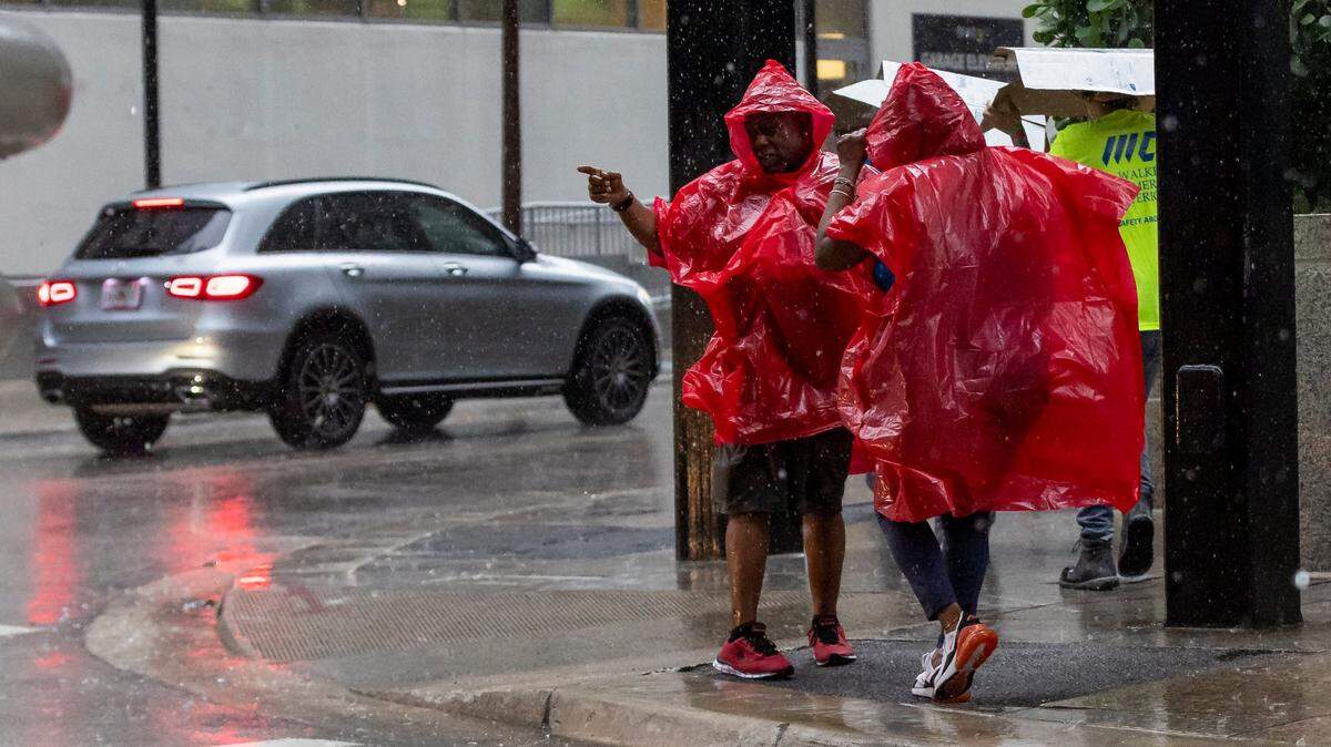 People are seen wearing ponchos as lightning and heavy rain falls over the area on Monday, June 19, 2023, in Miami, Fla.