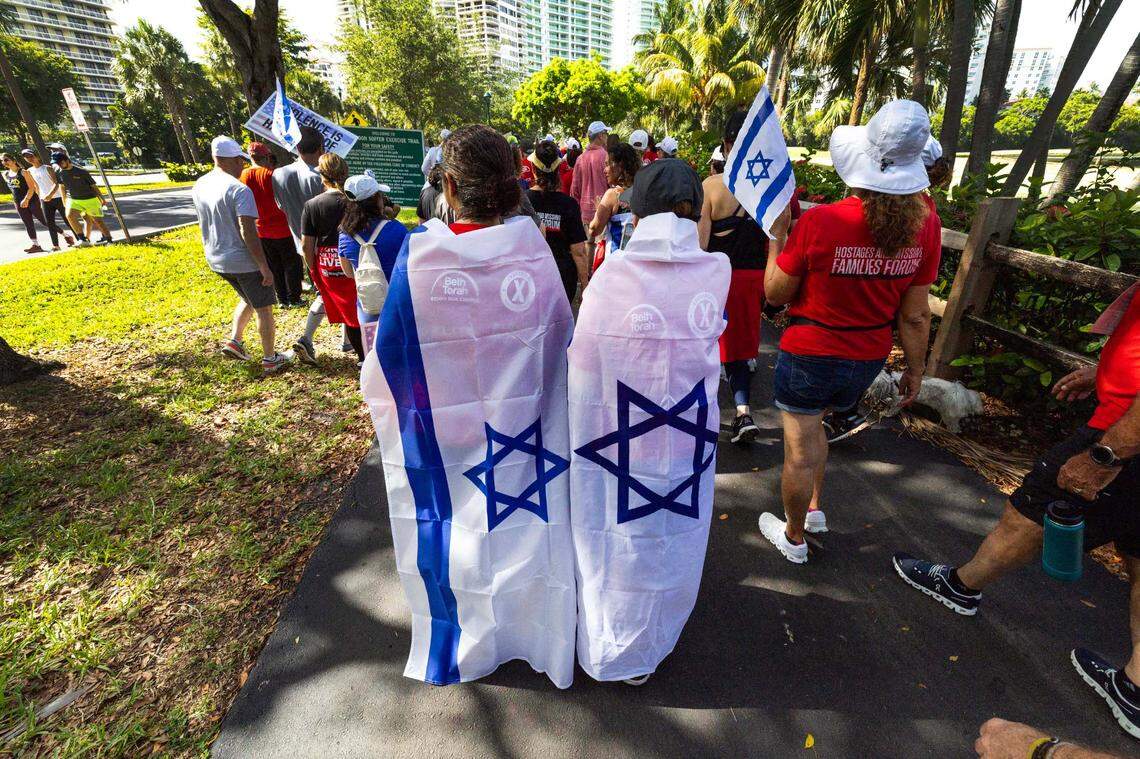 Demonstrators wear Israeli flags as they shuffle along the sidewalk during a solidarity “Run for Their Lives” walk to raise awareness for the 58 hostages still held in Gaza at Aventura Circle on Sunday, June 8, 2025, in Aventura, Fla.