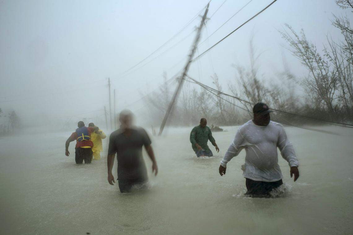 Volunteers walk in the wind and rain from Hurricane Dorian through a flooded road as they work to rescue families near the Causarina bridge in Freeport, Grand Bahama, Bahamas, Tuesday, Sept. 3, 2019.