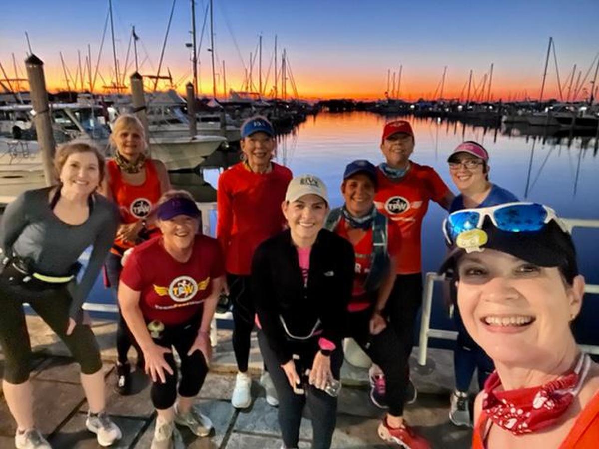 Joan Chrissos with her TeamFootWorks running group as the sun rises over Dinner Key Marina in Coconut Grove, Jan. 15, 2022. They ran/walked 12 miles that day. Betty Perez, the team leader, is at top right.