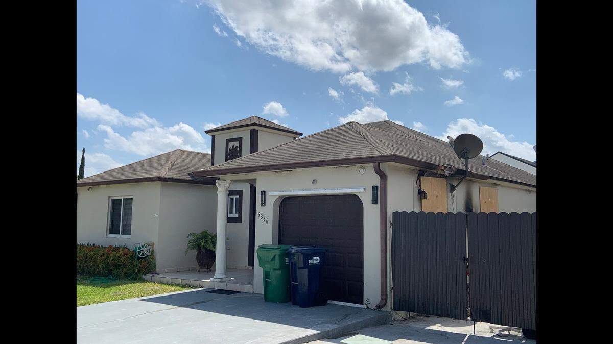 Behind the fence are the boarded up door and window to the garage apartment at 15856 SW 143rd Ct., where Kenneth Pirraglia died Tuesday in a fire.