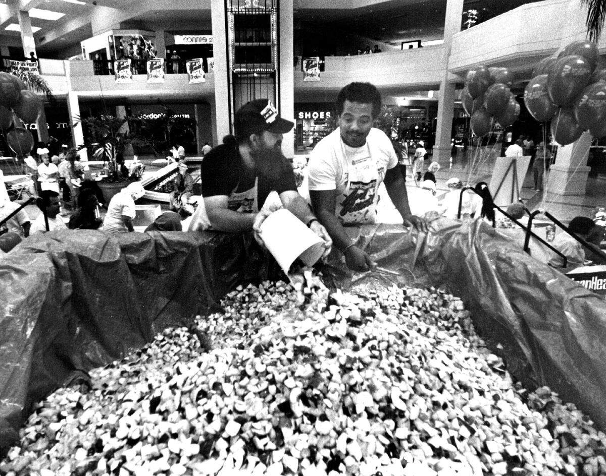 In this file photo from 1989, Don Morris, left, and Jesus Portuondo, both Volunteers from Telephone Pioneers of America, add more fruit to the one-ton fruit salad that was in the making at Aventura Mall.