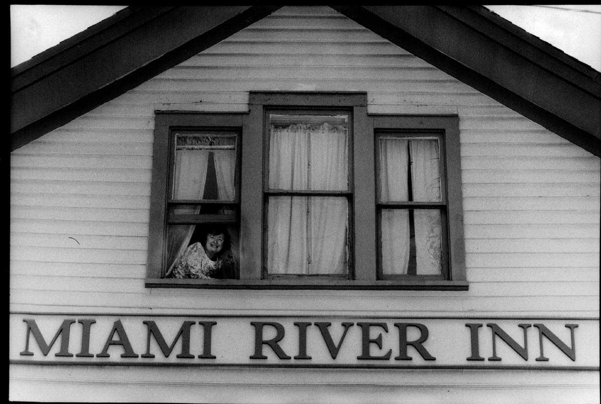 In 1991, the facade of the Miami River Inn as owner Sallye Jude peeks from the third floor front window of the Rose Arms building, one of five refurbished buildings.