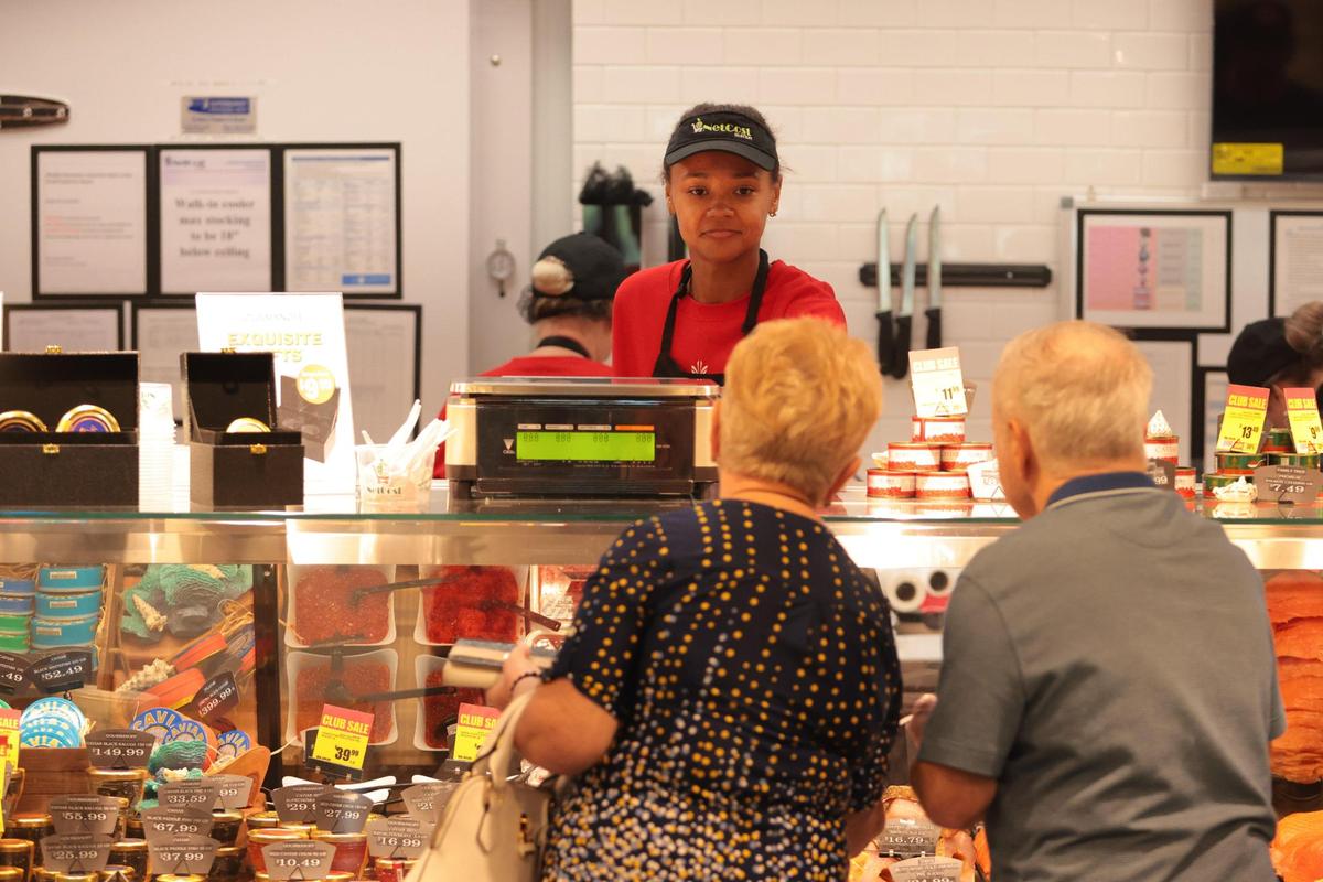 Naomi Mvesihva takes care of costumers at the deli counter at NetCost Market in Hollywood, Florida, on Thursday, Dec. 19, 2024.