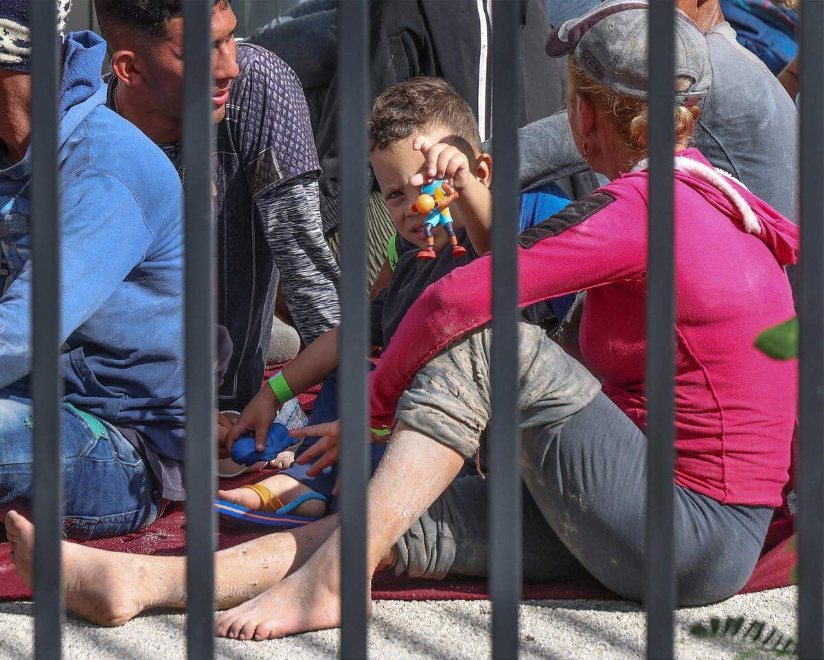 Cuban migrants sit on the ground while waiting to be processed at the Border Patrol facility in Marathon in the Florida Keys on Wednesday, Jan. 4, 2023. A little boy plays with a basketball toy figure.