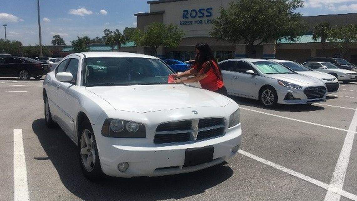 A member of Fiat Chrysler's "street team" puts a flyer on a Dodge Charger with an open recall.