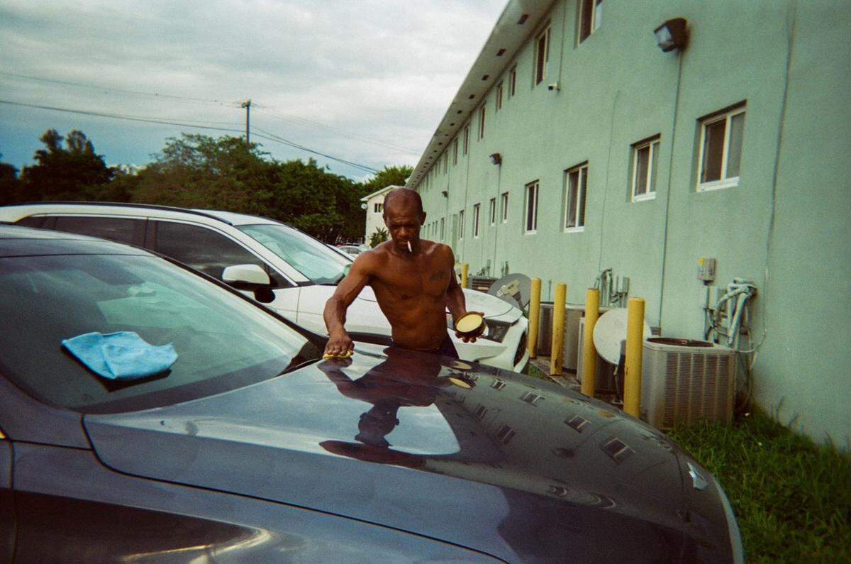 A photo features a shirtless man waxing the hood of his car. Elaine Williams, who has been a friend to the homeless for about 27 years, received disposable cameras from the Smile Trust, a nonprofit fighting to end homelessness, to photograph Miami through her lens. William’s art was featured during The Smile Trust’s “Smile Fuh Me” event hosted at the N’Namdi Contemporary Fine Art art gallery in Miami’s Little Haiti neighborhood on Sunday, December 5, 2021.