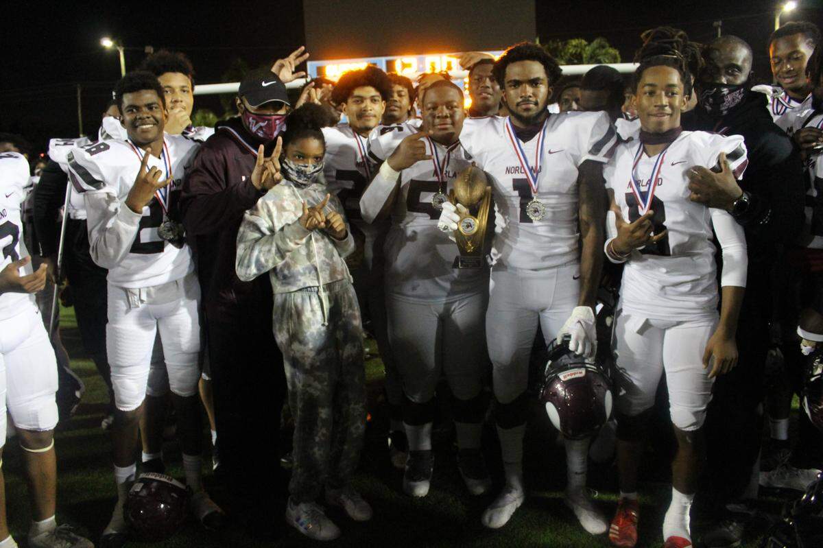 Along with his teammates, Norland’s Tayari Sherwood (1) proudly displays the Tri County 6A-1A Silver championship trophy following the Vikings’ 41-28 victory over Coconut Creek on Friday, Dec. 18, 2020, at Traz Powell Stadium.