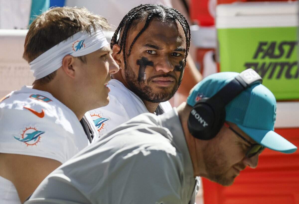 Miami Dolphins quarterback Tua Tagovailoa (1) on the bench with quarterback Zach Wilson (0) and Quarterbacks and Pass Game Coordinator Darrell Bevell in the second half of an NFL game against the Indianapolis Colts at Lucas Oil Stadium in Indianapolis on Sunday, September 7, 2025.