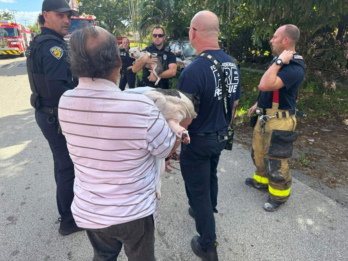 Fort Lauderdale firefighters and police stand with a homeowner whose dogs first responders rescued from a Melrose Park house fire Thursday morning, Feb. 6, 2025.