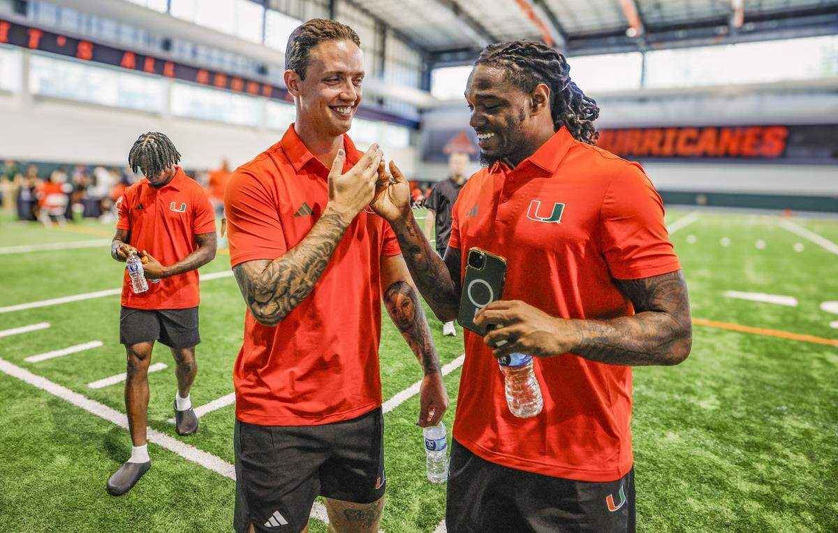 Miami Hurricanes quarterback Carson Beck and running back Mark Fletcher Jr. greet each other during media day at the Carol Soffer Indoor Practice Facility in Coral Gables, Florida, on Wednesday, July 30, 2025.