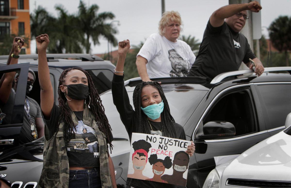 Miramar, Florida, June 3, 2020-Nikkie Price (left) and Kaylay McKenzie along with other participants, chant slogans in the parking lot at Miramar Town Center. COOL (Created Out of Love) Church lead a protest in the form of a funeral procession demonstration through Broward County. The police-escorted funeral procession symbolized a day of mourning for those fatally wounded by racially-motivated violence from Emmett Till to George Floyd. Cars drove throughout Broward County, Florida bearing the names of the lives lost on each car. The procession started at Gulfstream Park and proceeded west towards Miramar Town Center where protestors peacefully listened to speeches and prayed while maintaining social distancing.