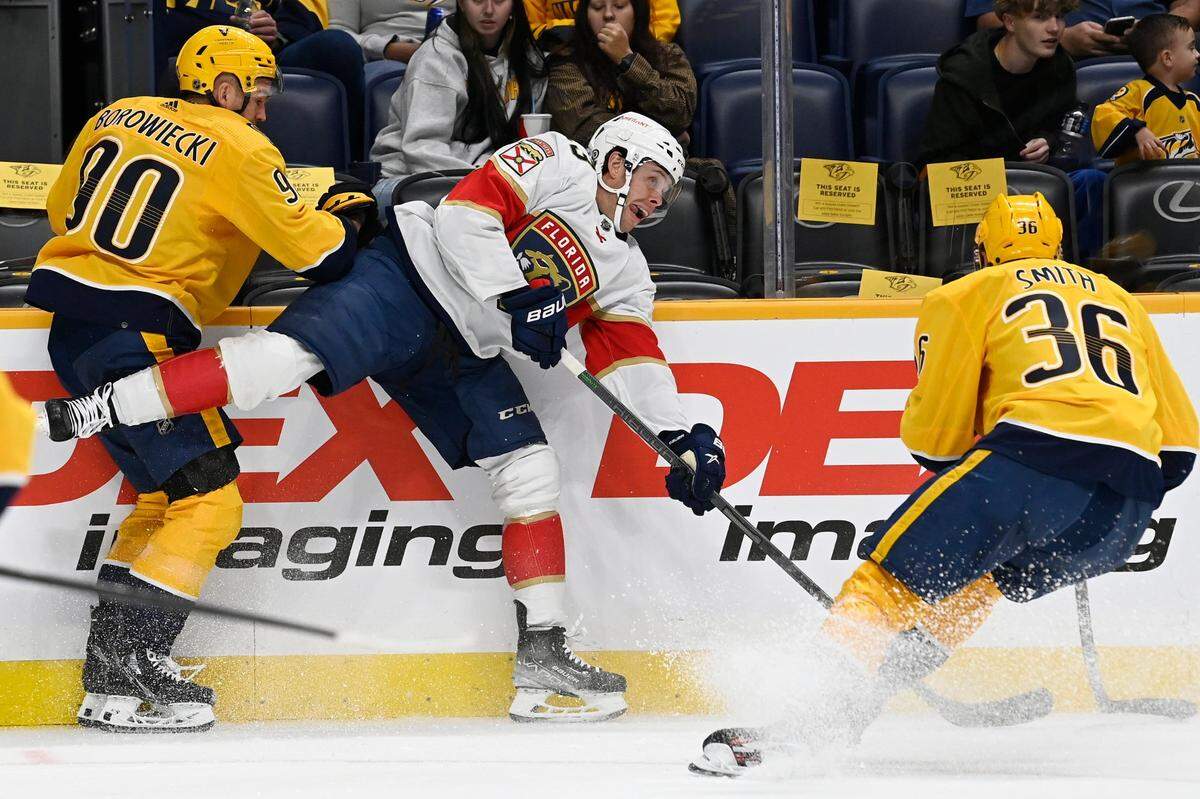 Florida Panthers center Carter Verhaeghe (23) passes the puck as he is defended by Nashville Predators defenseman Mark Borowiecki (90) and left wing Cole Smith (36) during the first period of an NHL preseason hockey game Monday, Sept. 26, 2022, in Nashville, Tenn. (AP Photo/Mark Zaleski)
