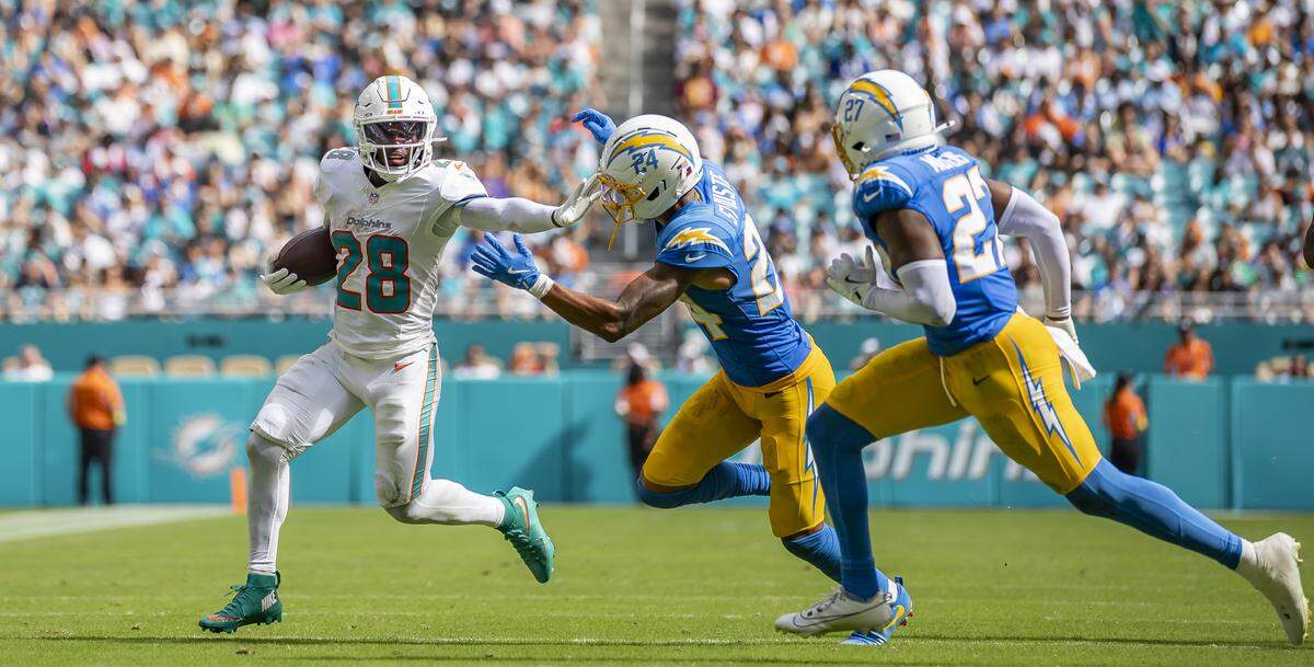 Miami Dolphins running back De'Von Achane (28) stiff arms Los Angeles Chargers cornerback Benjamin St-Juste (24) in the second half of their NFL game at Hard Rock Stadium on Sunday, Oct. 12, 2025, in Miami Gardens, Fla.